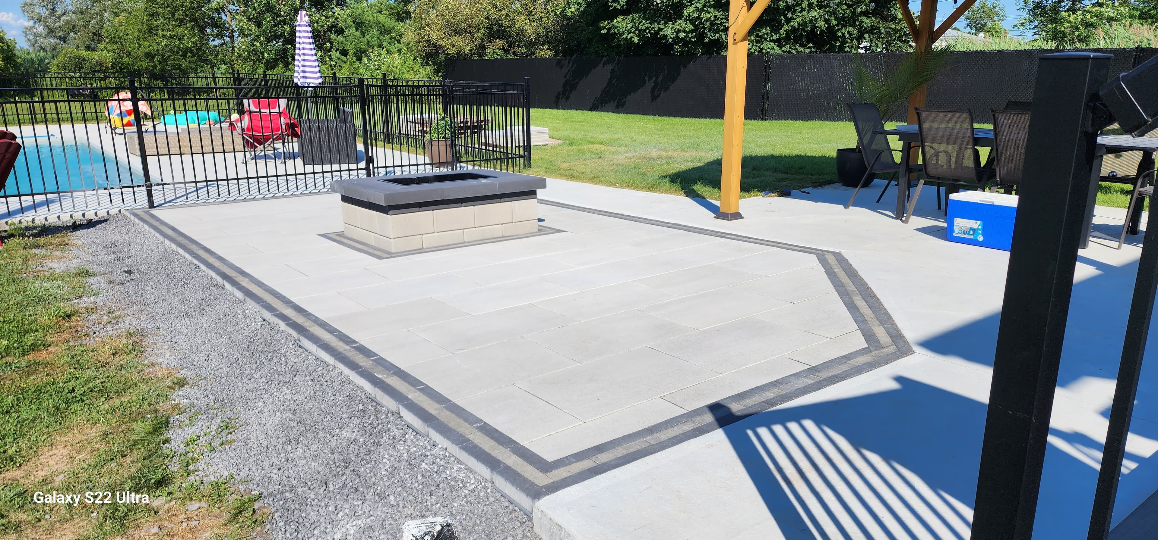 Large-format paver patio with built-in fire pit and iron pool fence