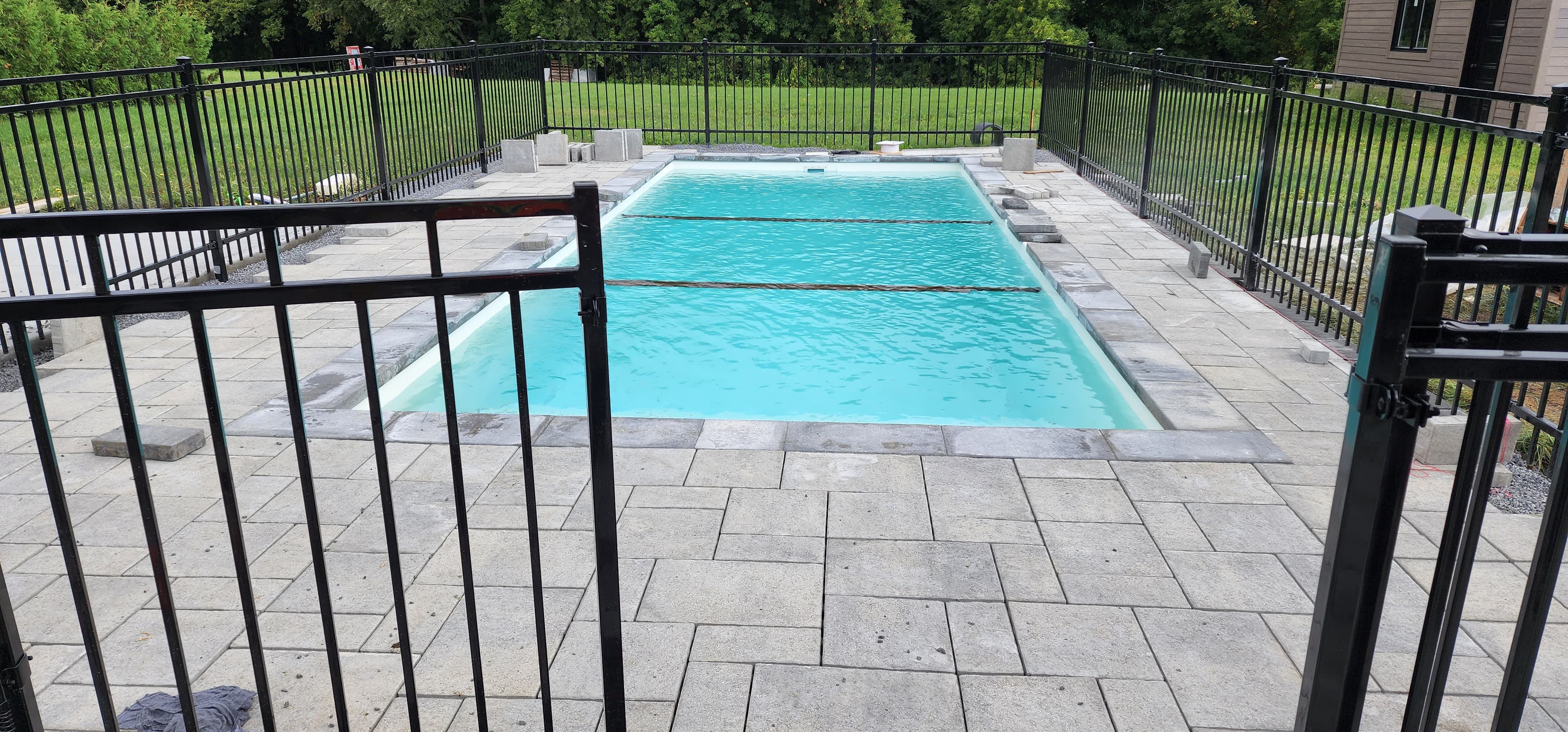 Terrasse de piscine en pave uni avec cloture de securite en fer